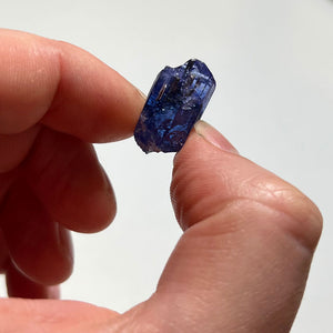 deep blue tanzanite crystal in hand for size